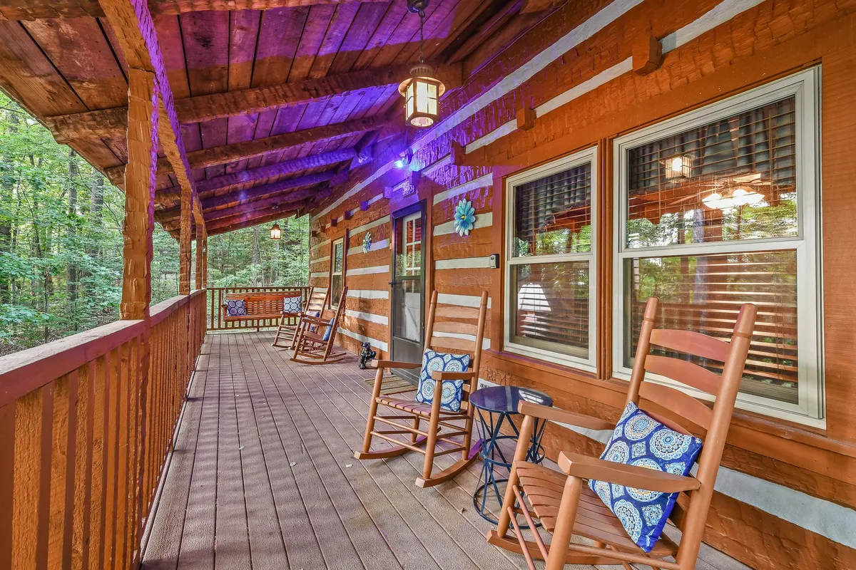 The image features a close-up of the wooden porch, complete with classic rocking chairs and decorative wall elements. It captures a cozy and inviting spot for socializing, watching wildlife, or stargazing under the night sky, reinforcing the section’s focus on evening family moments and outdoor fun.