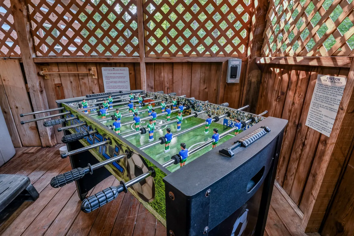 The image features a foosball table set in a common area, suggesting a space for playful competitions and social gatherings after a day exploring the outdoors. The mood is fun and relaxed, emphasizing group activities and shared memories.